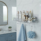 A transparent acrylic bathroom shelf mounted on white tiles in a modern bathroom, holding various skincare bottles.